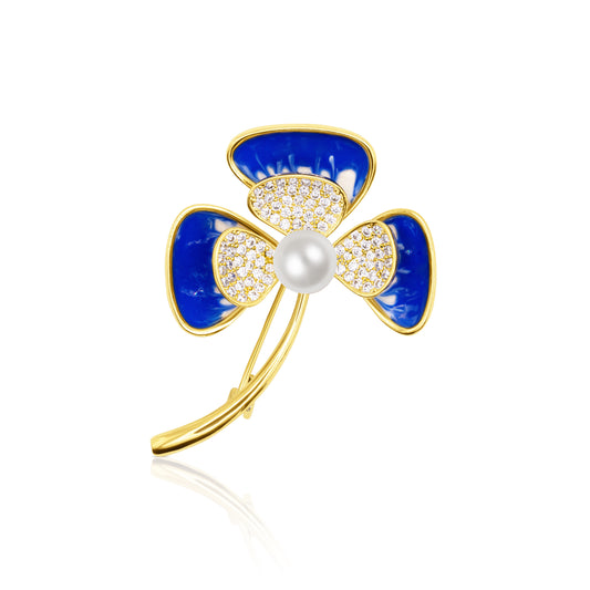Azure Delight Clover Brooch showcasing three vivid cobalt blue enamel petals with shimmering pavé centers, surrounding a white pearl. A golden stem arcs gracefully from the base. Photographed on a clean white background, this floral brooch offers a playful yet luxurious vibe, perfect for lively spring days, casual glam, or gifting someone who loves colorful elegance.