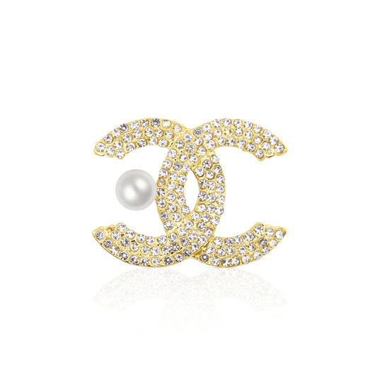 A glamorous gold-tone double C brooch encrusted with shimmering clear crystals, featuring a white faux pearl detail for added elegance. Stylish and iconic, this brooch is perfect for elevating both everyday and formal outfits with a luxurious flair.
