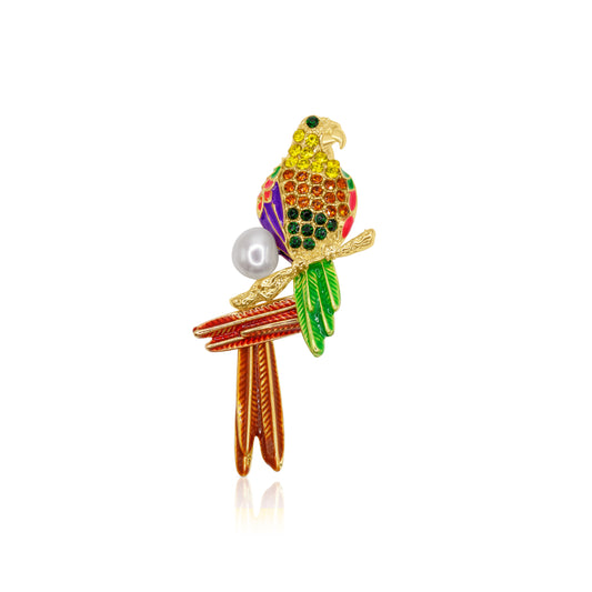 A dazzling parrot brooch featuring a vibrant array of multicolored crystals set against a gold-tone base. The parrot is perched gracefully with a round faux pearl accent beneath it, adding a touch of elegance to its colorful and lively design. A perfect statement piece to accessorize any outfit.