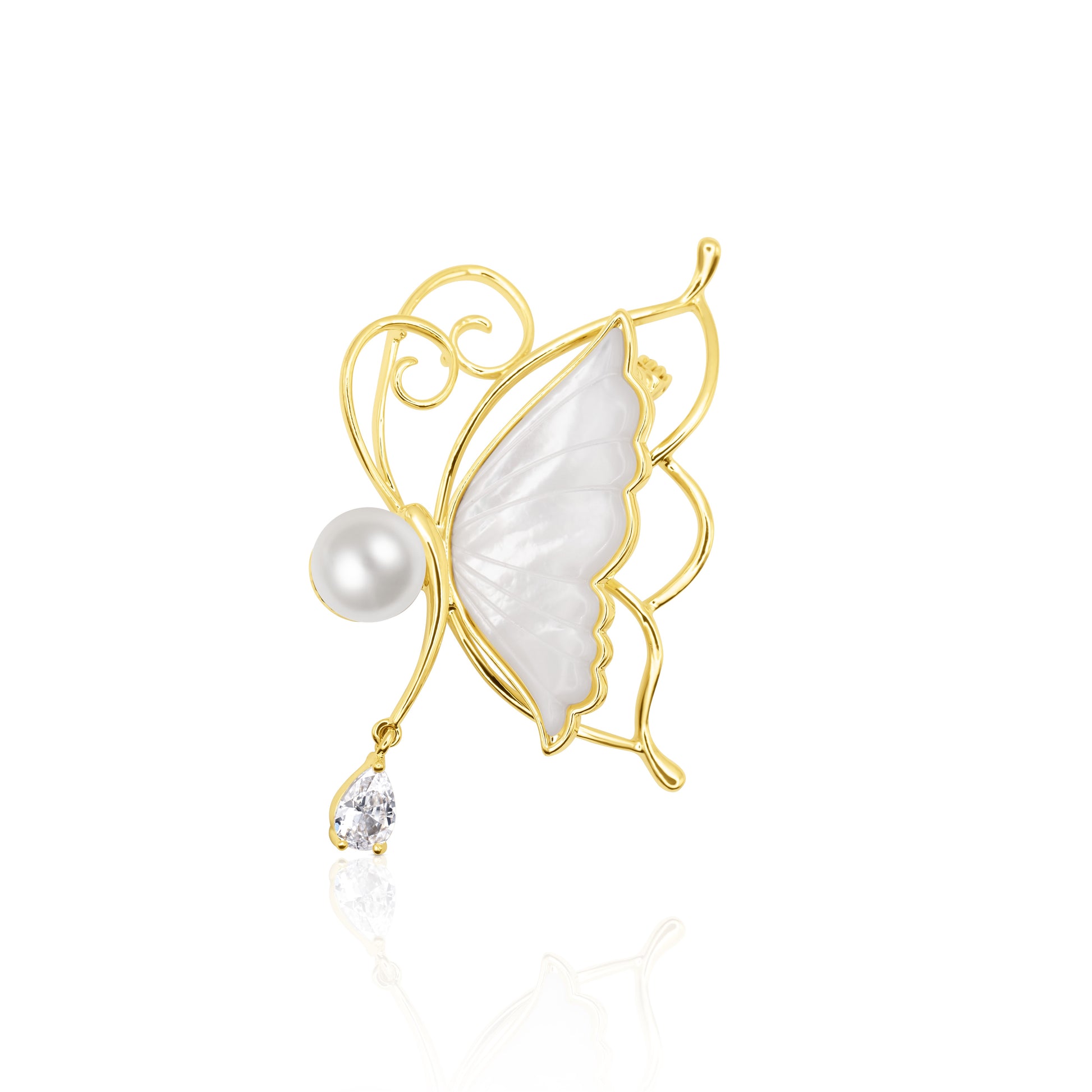 Whisperwing Butterfly Brooch featuring translucent white enamel wings framed in gold, a pearl body at the center, and a single teardrop crystal hanging delicately below. The piece rests on a white reflective background, highlighting its fairy-like elegance and subtle sparkle. A light and enchanting accessory perfect for weddings, spring events, or soft glam fashion.