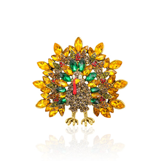 An eye-catching gold-plated brooch in the shape of a turkey, adorned with amber, green, and red crystals, perfect for festive occasions and Thanksgiving gatherings.