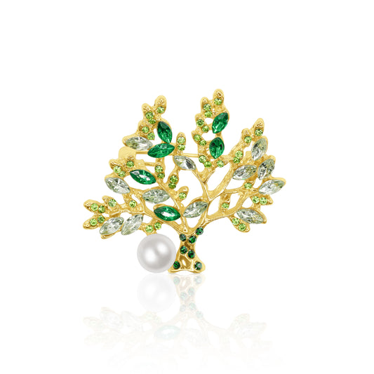 A striking gold-plated Tree of Life brooch adorned with vibrant green crystal leaves and a delicate faux pearl accent. This nature-inspired accessory features intricate branch detailing, symbolizing growth and renewal. The perfect addition to any outfit, this brooch combines timeless elegance with a touch of whimsy, making it a captivating statement piece for any occasion.