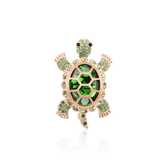 A striking turtle-shaped brooch adorned with vibrant green crystals and set on a gold-tone base, featuring a secure pin clasp and lifelike detailing.