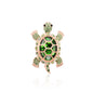 A striking turtle-shaped brooch adorned with vibrant green crystals and set on a gold-tone base, featuring a secure pin clasp and lifelike detailing.