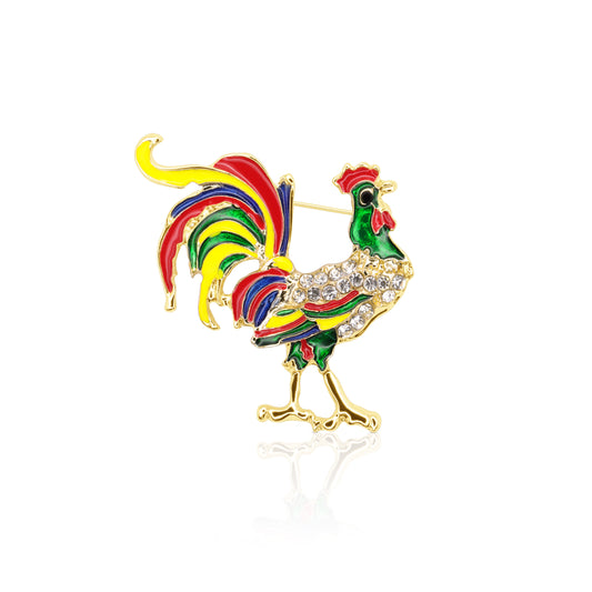A vibrant rooster-shaped brooch adorned with rainbow-colored enamel and sparkling clear crystals, set on a gold-plated base with a secure pin closure.
