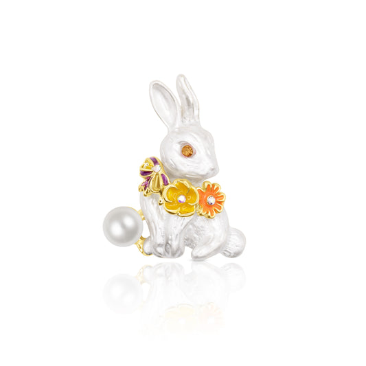 Cute white rabbit brooch with enamel finish, decorated with a garland of colorful flowers in orange, yellow, and purple with gem accents. A pearl tail adds elegance to the design. Lightweight and detailed, ideal for spring fashion or Easter-themed accessories. Perfect for gifting animal lovers or as a charming lapel pin for cardigans, dresses, and scarves.