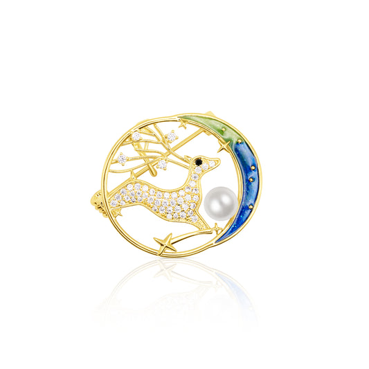 The Starlit Grace Brooch features a golden deer leaping across a circular frame with a hand-painted gradient moon in green and blue. Sparkling crystals form the deer, stars, and sky, while a radiant faux pearl nestles along the lower edge. Reflecting light against a glossy white surface, this enchanting piece evokes celestial elegance and fantasy, ideal for magical evenings or ethereal accessorizing.