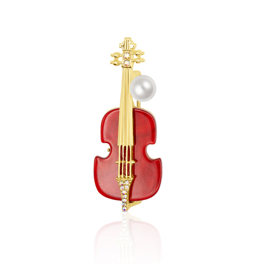 Elegant violin-shaped brooch in glossy red enamel with gold-tone strings and structure, featuring a faux pearl and crystal detailing. Perfect for musicians or lovers of music-themed accessories. The brooch is photographed on a white background to showcase its rich color and intricate craftsmanship.