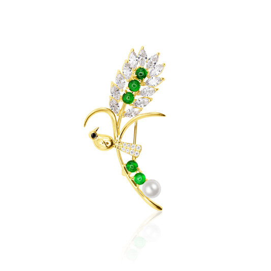 Verdant Songbird Elegance Brooch featuring a gold-tone bird perched along a branch-like curve embellished with sparkling marquise-cut crystals, glossy green floral beads, and a single pearl accent. The brooch rests against a reflective white background, highlighting its garden-inspired elegance and refined craftsmanship. Perfect for spring outfits, nature-themed collections, or stylish gifting with symbolic flair.