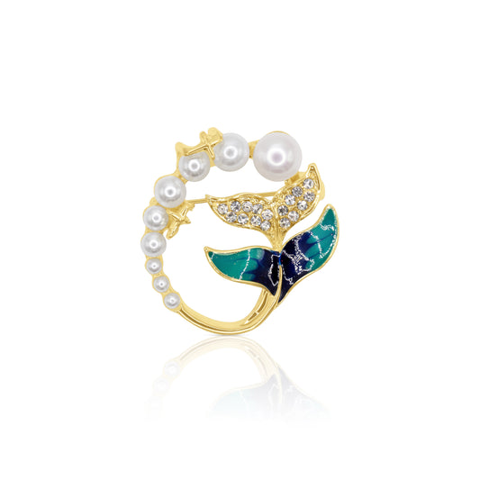 Gold whale tail brooch featuring shimmering crystals, lush green enamel, and a string of pearls, symbolizing the beauty of the ocean and marine life. Elegant and whimsical jewelry piece perfect for adding a coastal charm to your outfit.