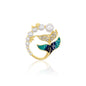 Gold whale tail brooch featuring shimmering crystals, lush green enamel, and a string of pearls, symbolizing the beauty of the ocean and marine life. Elegant and whimsical jewelry piece perfect for adding a coastal charm to your outfit.